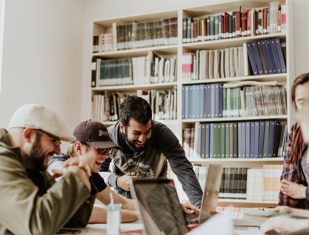 A group of people looking at a screen, possibly working and laughing together